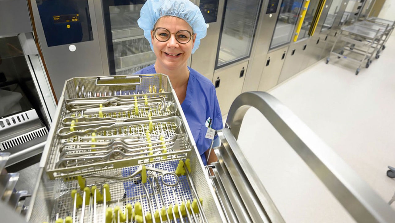 Pielęgniarka stojąca z uśmiechem obok półki z zestawem instrumentów