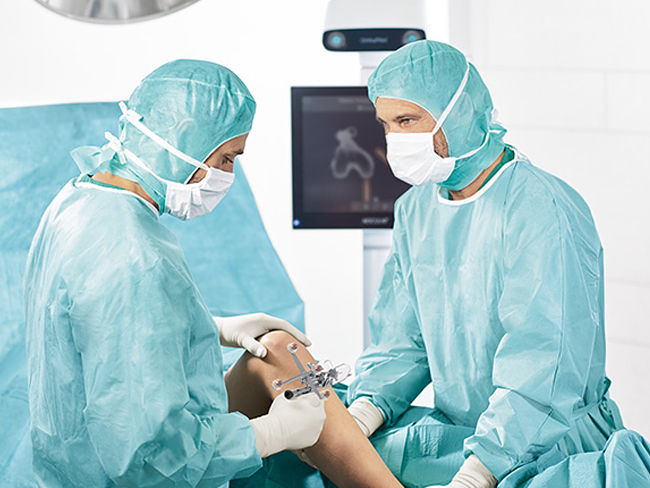 Dwóch chirurgów z systemem nawigacyjnym OrthoPilot® Elite na sali operacyjnej