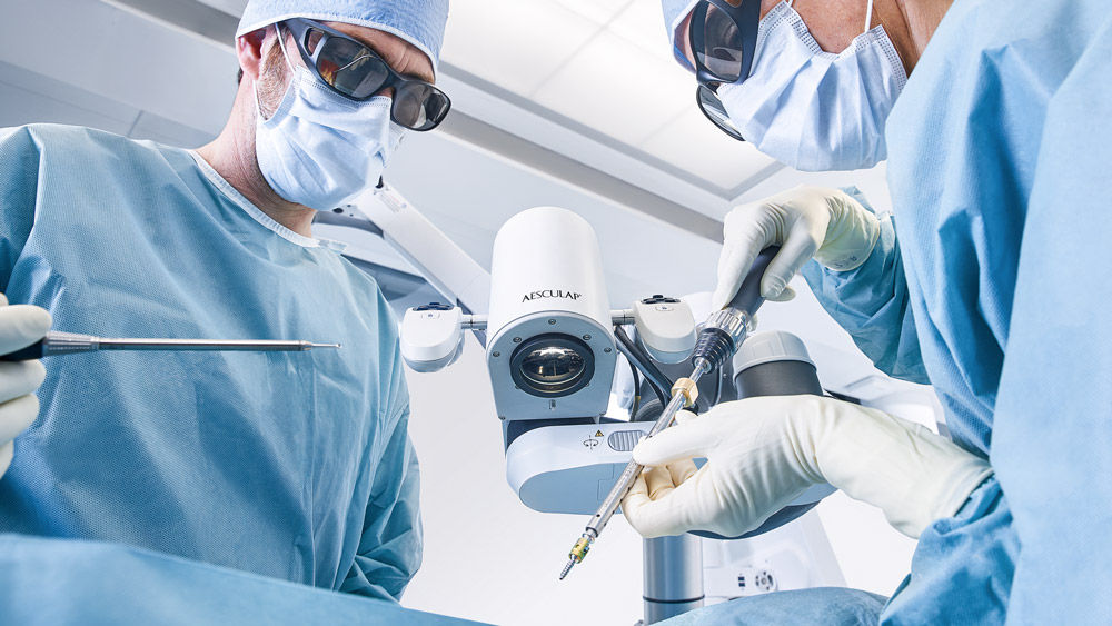 Chirurdzy na sali operacyjnej z mikroskopem chirurgicznym wspomaganym robotycznie