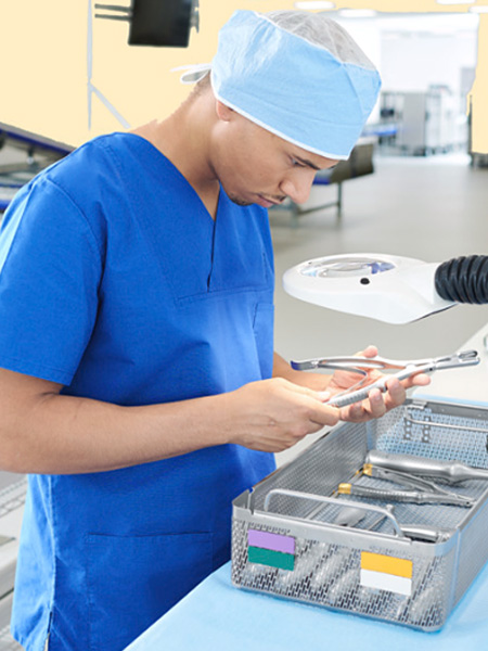 Pracownik centralnej sterylizatorni sprawdza różne instrumenty w koszu