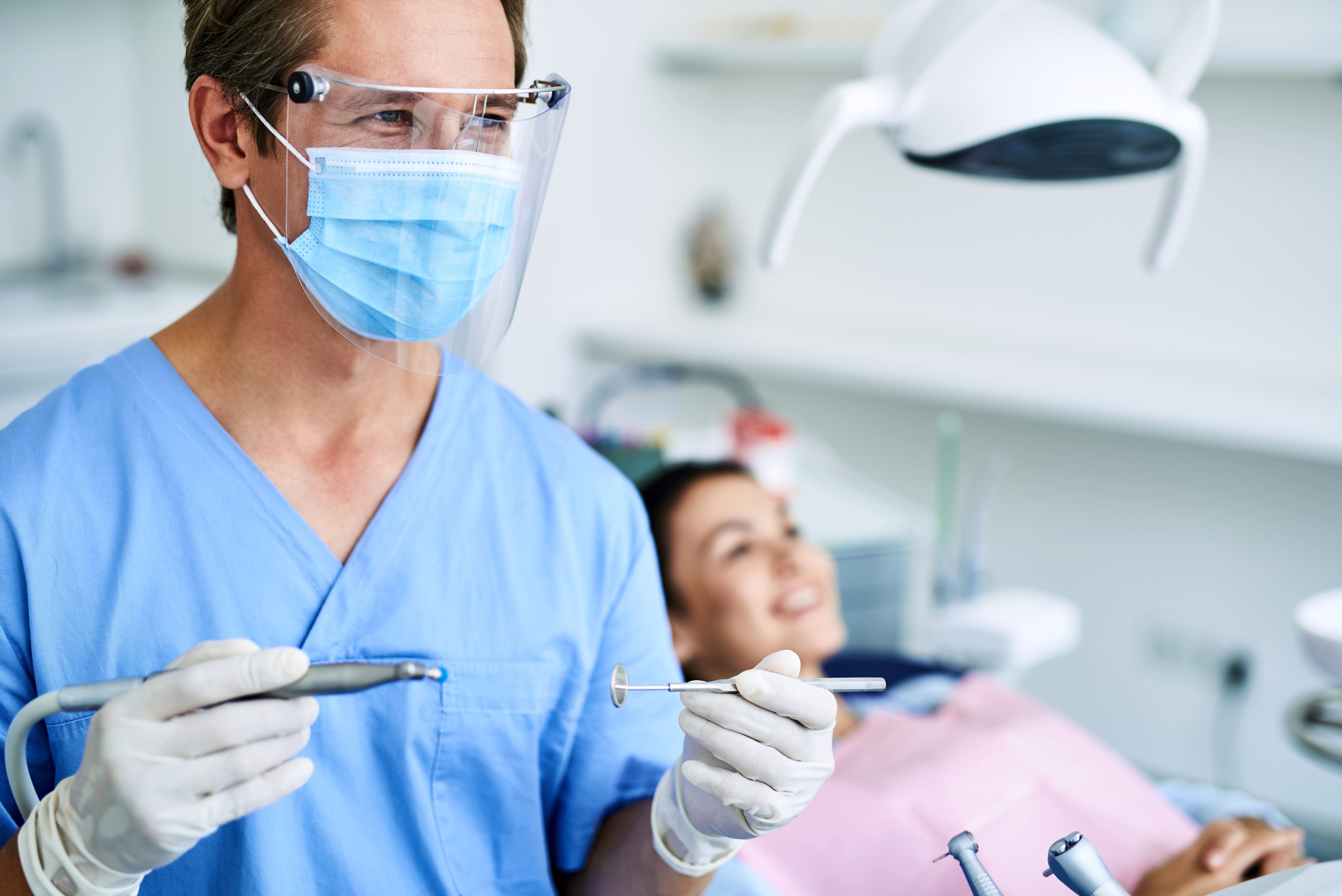 Positive dentist in protective mask preparing for dental procedure