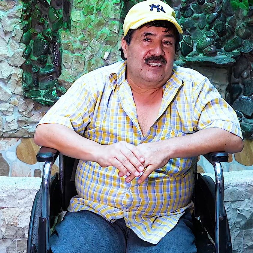 Mężczyzna z Ekwadoru w czapce siedzący na wózku inwalidzkim